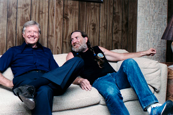 Willie Nelson and Jimmy Carter in Jimmy Carter: Rock & Roll President Willie Nelson and Jimmy Carter sit on a couch.