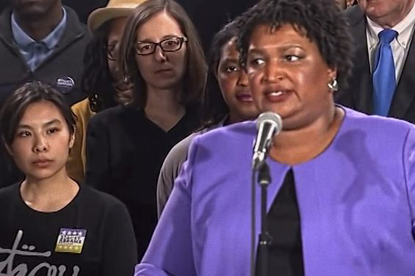 Stacey Abrams, an American politician, lawyer, voting rights activist, and author who served in the Georgia House of Representatives from 2007 to 2017, serving as minority leader from 2011 to 2017 speaks at a podium.