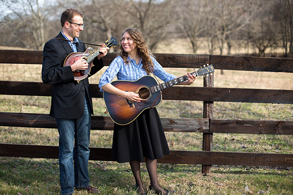 Photo of Corinna Logston and Jeremy Stephens playing guitars in a field.